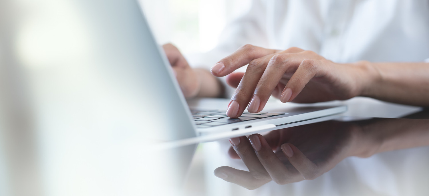 KI generiert: Das Bild zeigt eine Person, die auf einer Laptop-Tastatur tippt. Der Fokus liegt auf den Händen, die in einer hellen und modernen Umgebung arbeiten.