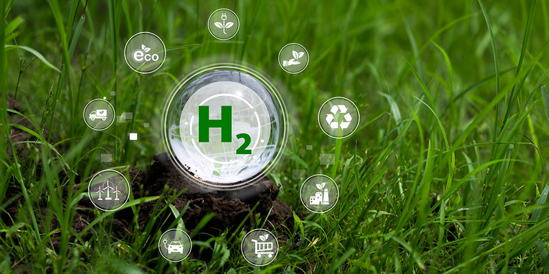 KI generiert: Das Bild zeigt eine grüne Landschaft mit einem großen "H2" Symbol im Mittelpunkt, das von verschiedenen nachhaltigen und umweltfreundlichen Symbolen umgeben ist. Der Hauptinhalt ist die Darstellung von Wasserstoff (H2) als grüner und nachhaltiger Energieträger.