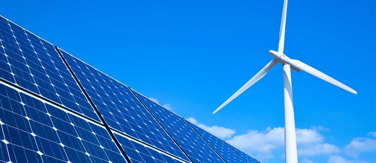 KI generiert: Das Bild zeigt erneuerbare Energiequellen mit Solarpaneelen und einem Windrad vor einem klaren blauen Himmel. Der Hauptinhalt ist die Nutzung von Sonnen- und Windenergie.