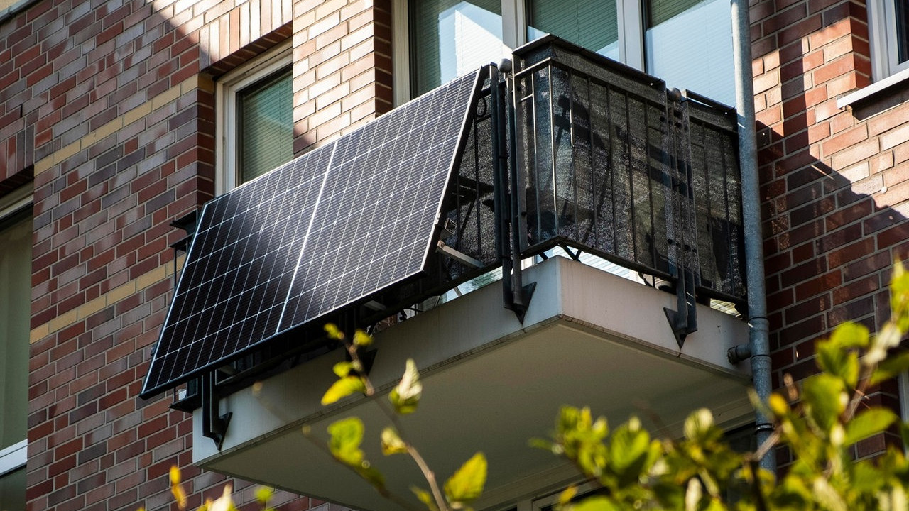 KI generiert: Das Bild zeigt ein Solarmodul, das an einem Balkon einer Backsteinwohnung befestigt ist. Die Szene unterstreicht die Nutzung von Solarenergie in städtischen Wohngebieten.