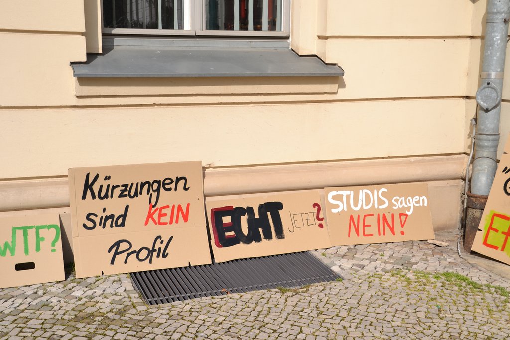 KI generiert: Das Bild zeigt mehrere Protestschilder, die gegen Kürzungen und für die Anliegen von Studierenden protestieren. Die Schilder lehnen Kürzungen ab und fordern Aktionen ein.
